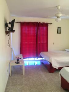 a room with two beds and a window with red curtains at Hotel Vista Sur in Los Patos
