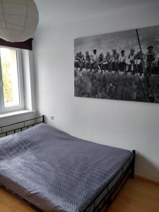 uma cama num quarto com uma fotografia na parede em Apartament Centrum em Szczecinek