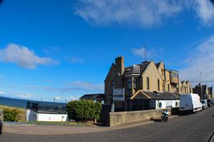 una casa al lado de una calle con el océano en GOLF View Hotel & Macintosh Restaurant, en Lossiemouth