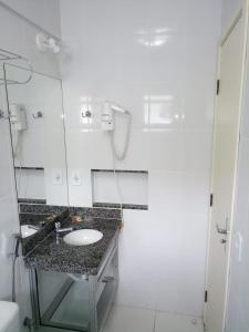 Baño blanco con lavabo y espejo en Reserve Caldas Lacqua 5, en Caldas Novas