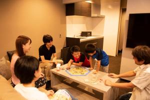 een groep mensen die rond een tafel zitten en een spel spelen bij INOVA Kanazawa Station Hotel Suite in Kanazawa