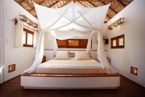 a bedroom with a bed with a canopy at La Ferme De Georges in Atins