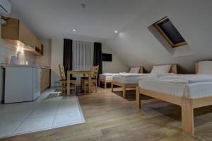 a room with three beds and a table and a kitchen at Tihe Noci Motel in Pale