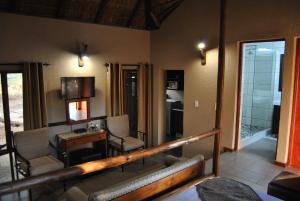 a living room with a balcony with chairs and a table at Mabalingwe Elephant Lodge in Bela-Bela