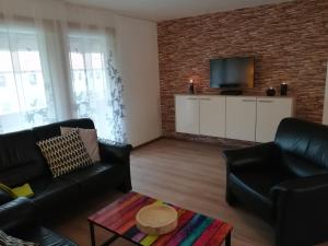 sala de estar con muebles negros y pared de ladrillo en Ferienwohnung am Reinhardswald - Eichenlaub - mit Sauna, en Trendelburg