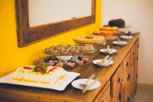 a buffet with cakes and other desserts on a table at Pousada Villa Atlântica in Camburi