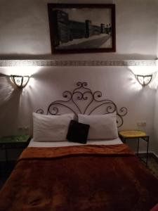 a bedroom with a bed with a headboard and two lights at Riad Anass Al Ouali in Fès