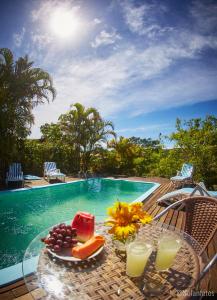 a table with a slice of cake and fruit next to a pool at Pousada Watu Kerere in Praia do Rosa