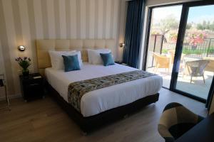 1 dormitorio con 1 cama grande y balcón en Tantur Hills Hotel - Jerusalem en Jerusalén