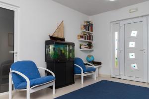salon z 2 niebieskimi krzesłami i akwarium w obiekcie Apartments Veramenta w mieście Cavtat