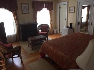 a bedroom with a bed and a chair and two windows at Four Creeks Bed&Breakfast in Fairview