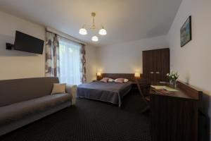 um quarto de hotel com uma cama e um sofá em Willa Miła em Wisla