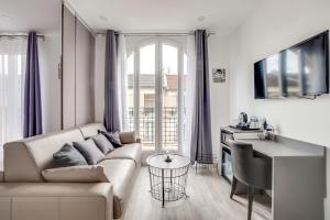 a white living room with a couch and a table at Paris Hotel in Clichy