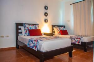1 dormitorio con 2 camas y almohadas rojas y azules en Cocotal Bavaro Apartments, en Punta Cana