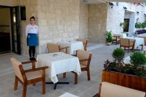 une femme debout dans un restaurant avec des tables et des chaises dans l'établissement Tantur Hills Hotel - Jerusalem, à Jérusalem