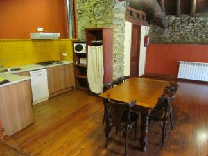 a kitchen with a wooden table and a wooden floor at Can Bonada in El Serrat