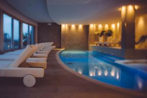 a swimming pool in a hotel with white lounge chairs at Olivi Hotel & Natural Spa in Sirmione