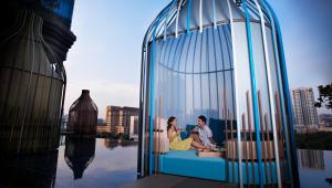 
a woman sitting on a balcony looking at the water at PARKROYAL COLLECTION Pickering, Singapore - SG Clean, Staycation Approved in Singapore
