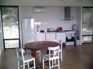 a kitchen with a wooden table and white appliances at Wallaby Retreat in Kingscote