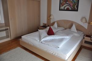 a white bed with a red pillow on it at Hotel Brunner in Merano