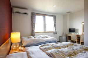Duas camas num quarto com uma secretária e uma janela em Hotel Jodai em Unnan
