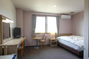 Unnanにあるホテル上代のベッド、デスク、テレビが備わるホテルルームです。
