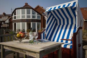 une table avec un parasol rayé bleu et blanc et une chaise dans l'établissement Ferienhaus *Traumblick*, à Wittdün