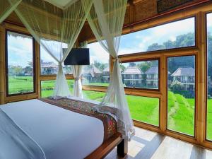 a bedroom with a bed and large windows at Biyukukung Suite & Spa in Ubud