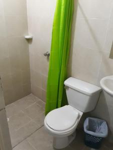 a bathroom with a toilet and a green shower curtain at HOTEL LA QUINTA in La Dorada