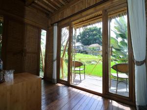 an open door to a patio with chairs on a deck at Biyukukung Suite & Spa in Ubud