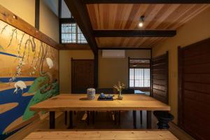 a dining room with a wooden table and a painting at Gion Shirakawa Kouki Machiya House in Kyoto