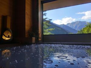 um quarto com uma grande janela com vista para as montanhas em Super Hydrogen Rich Spa Yado Kanzan em Minakami
