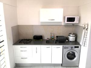 Una cocina blanca con fregadero y lavadora. en Iris suite, en Punaauia
