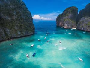 a group of boats in the water in a bay with limestone cliffs at Lucky Dorm in Phi Phi Islands