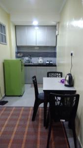 a kitchen with a table and chairs and a green refrigerator at HOMESTAY KAMPUNG DELEK BARU, KLANG in Kampong Telok Gadong Kechil