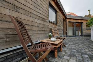 2 stoelen en een houten tafel op een patio bij Vakantiewoning Martha in Veurne