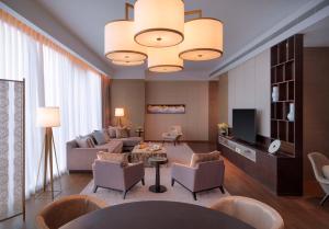 a living room with a couch and chairs and a television at Hyatt Regency Zhenjiang in Zhenjiang
