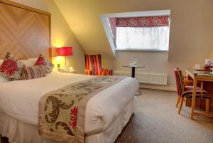 a hotel room with a bed, desk, chair and window at Best Western Homestead Court Hotel in Welwyn Garden City