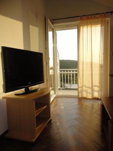ein Wohnzimmer mit einem Flachbild-TV und einem Balkon in der Unterkunft Apartments Marija in Slano