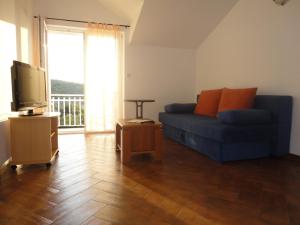 ein Wohnzimmer mit einem blauen Sofa und einem Fernseher in der Unterkunft Apartments Marija in Slano