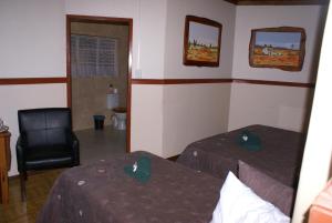 a hotel room with two beds and a chair at Airport Inn Bed and Breakfast in Kempton Park