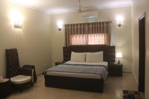 a bedroom with a large bed and a chair at Motel Inn in Karachi