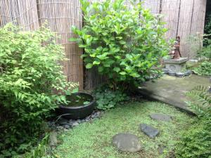 um jardim com um arbusto ao lado de uma cerca em Guest House Kamejikan em Kamakura