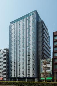 a tall gray building in front of some buildings at Hotel Route-Inn Grand Tokyo Asakusabashi in Tokyo
