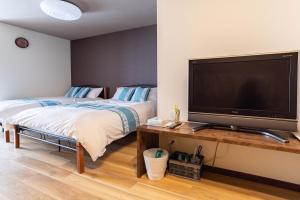 1 dormitorio con 2 camas y TV de pantalla plana en Tino Asuka en Osaka