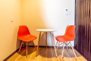 2 sillas naranjas y una mesa en una habitación en Tino Asuka en Osaka