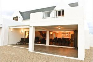 a white house with a patio and a dining room at Hemel op Aarde Villa in Dwarskersbos