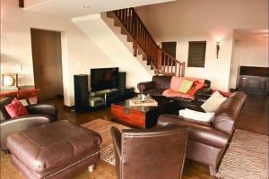 a living room with leather furniture and a staircase at Hemel op Aarde Villa in Dwarskersbos