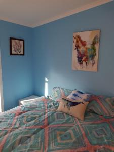 1 dormitorio con 1 cama con una pintura en la pared en Poss' Place, en Rocky Cape