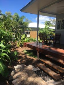 een veranda met een houten bank in een tuin bij Island Cottages in Nelly Bay